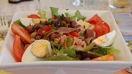 Salát Niçoise se neobejde bez čerstvých rajčat a ančoviček, které někdy nahrazuje tuňák. Chuť doladí lehce nakyslá zálivka