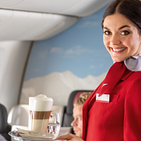 Letuška nabízí cestujícím kávu. (zdroj: Wikimedia Commons/Austrian Airlines, CC BY-SA 2.0)