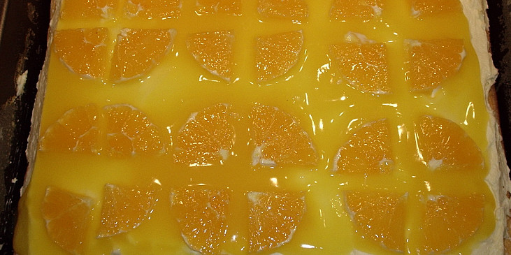 na krém rozetřeme polovinu želé a ozdobíme plátky pomeranče