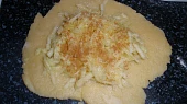 Zatočený závin, rozválený kousek těsta, na tom nastrouhané jablko, skořice a cukr
