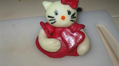 Modelování Hello Kitty (poslepujem cukrovou vodou, ručičky k šatičkám, hlavičku na špejli napíchneme a připevnímek šatičkám)