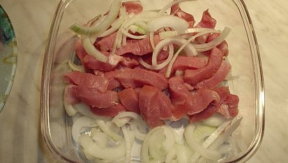 Vepřové nudličky s vínovou příchutí po indicku, Nudličky dáme na vrstvu cibule, okořeníme, podlijeme vínem a nacháme marinovat.