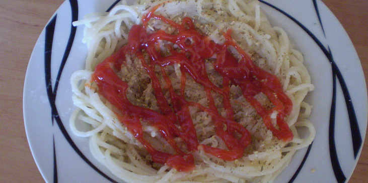 Na talíři špagety do tvaru hnízda sypeme oregánem a poléváme kečupem