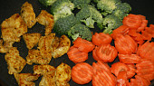 Shirataki nudle s kuřecím masem, brokolicí a mrkví, orestované maso a přidaná zelenina na pánvi