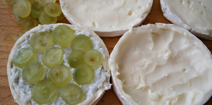 Do vydlabané půlky sýra opatrně upěchujeme polovinu náplně a poklademe hrozny nakrájenými na plátky.