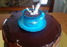 Čokoládový dort s šálkem kávy a levitující smetanou