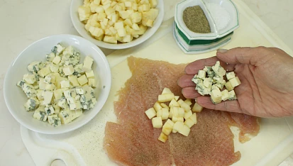 Kuřecí měšec plněný sýrem, Plátky rozložte na prkénko, osolte je, opepřete a do středu každého vložte po hrsti na kostičky nakrájeného jablka a nivy