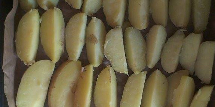 Uvařené a nakrájené brambory rozprostřené na plechu