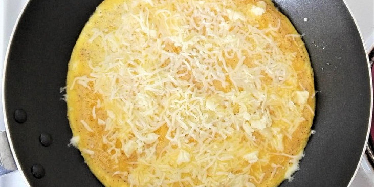 Když je omeleta skoro hotová a je tekutější už jen vršek, posypeme ji strouhaným sýrem a necháme chvilku dosmažit. 