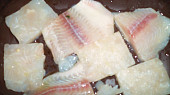 Rybí filety přikryté zeleninou, dvěma sýry a zakysanou smetanou, filety nakrájíme na menší kusy...