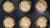 Banánové muffinky s čokoládou (Připravíme si formu na muffiny, do které dáme košíčky na muffiny. Na dno košíčku dáme trošku těsta. Doprostřed těsta dáme trochu nasekané čokolády nebo čokoládových čoček. Na čokoládu dáme další vrstvu těsta. Košíček by měl být naplněný cca do 3/4.)