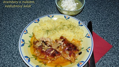 Válečky z mletého kuřecího masa obalené slaninou a pečené brambory s česnekem.